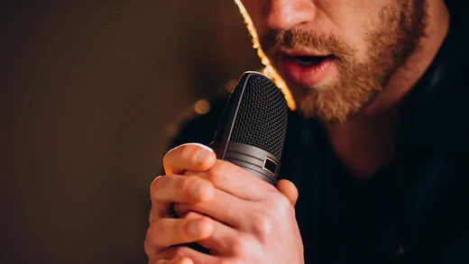 Man with microphone singing. How Nasal Breathing Reduces Vocal Effort and Helps You Sing with Ease