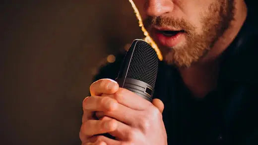 Man with microphone singing. How Nasal Breathing Reduces Vocal Effort and Helps You Sing with Ease