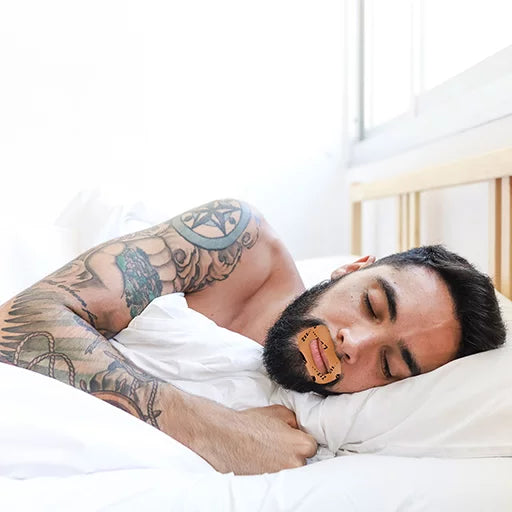 Bearded Man with tattoos on his arm wearing MyoTape mouth tape and Mouth Tape